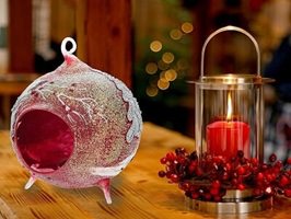 Julelanterne i rød-bordeaux glas med snekrystaller, stående på bord. Unik julekugle figur